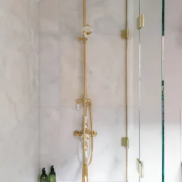 Carrara Honed Long Island Marble in a bathroom with a gold shower head
